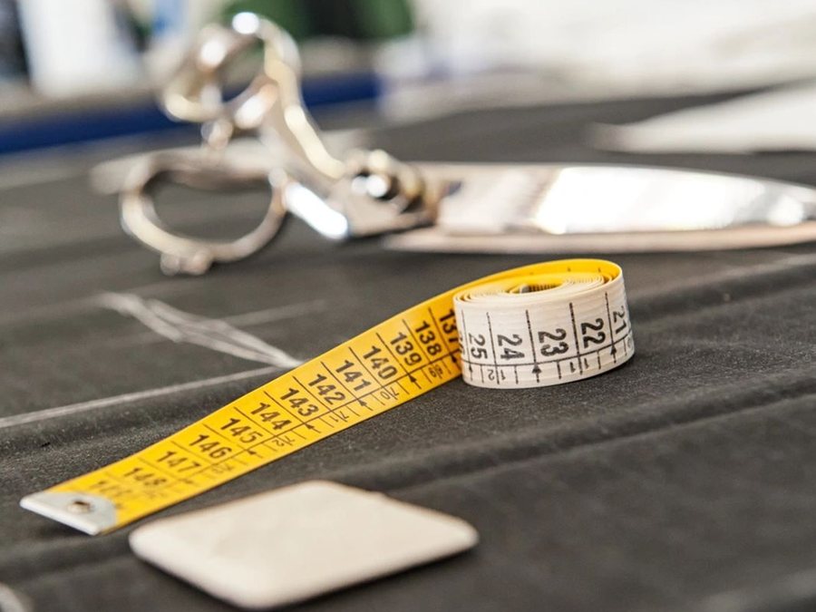 Tape measure, tailor's chalk and shears on a length of suiting fabric