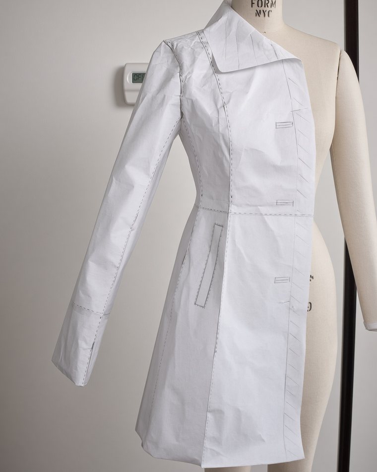 A paper pattern coat draped on a dress form, seam lines marked in pencil
