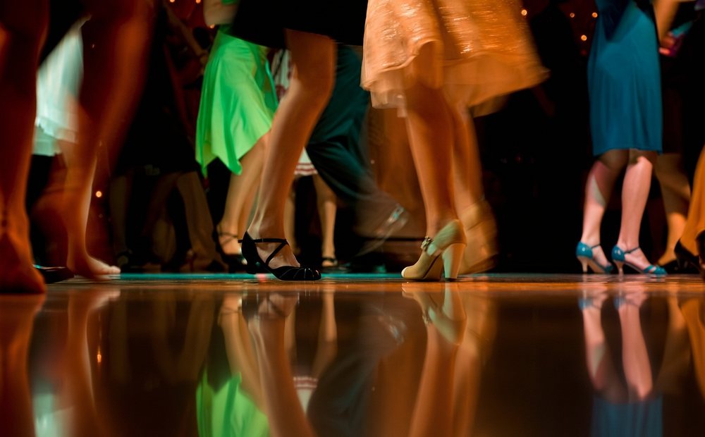Dancers in formal dresses on a lit dance floor